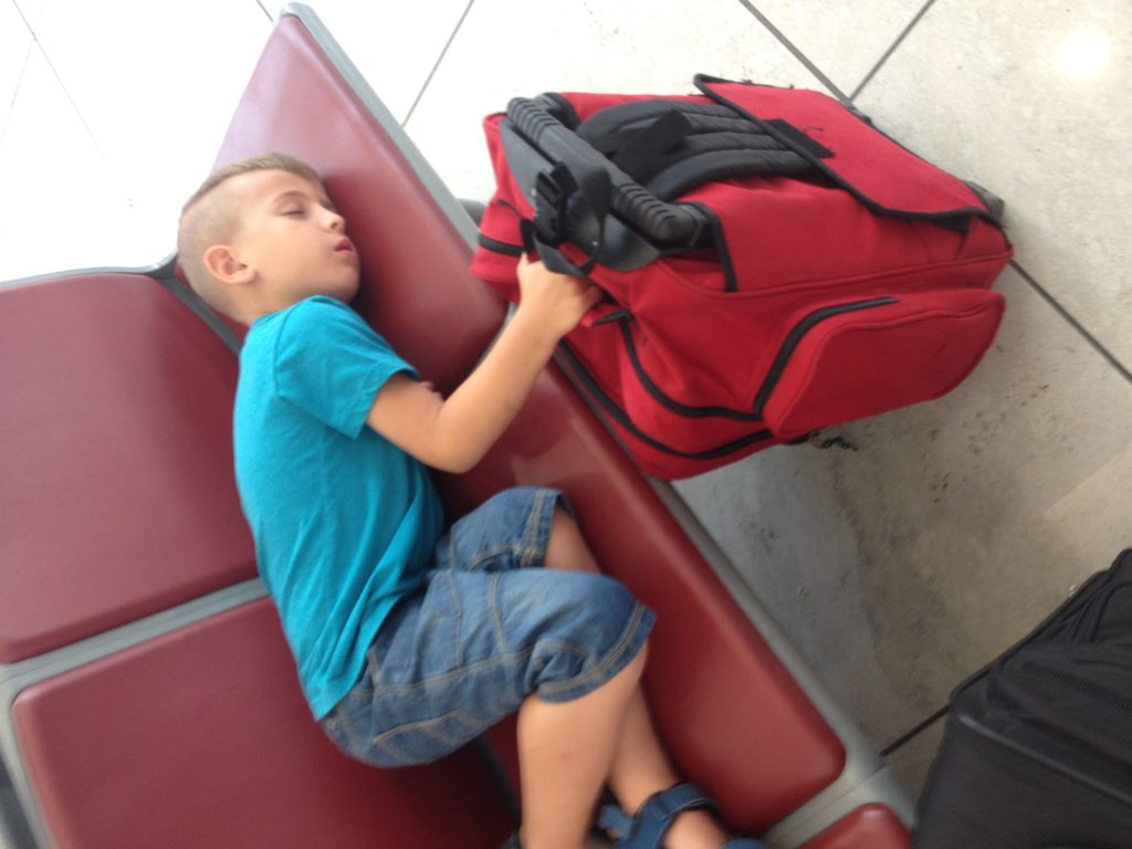 image of boy napping in airport hold luggage