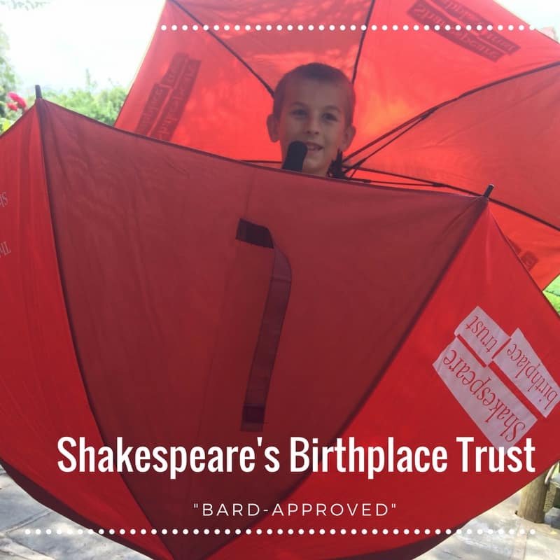 Boy holding 2 red umbrellas at Shakespeare's Birthplace Trust. 7 Stratford-Upon-Avon Tips for Bard Approved Family Activities.