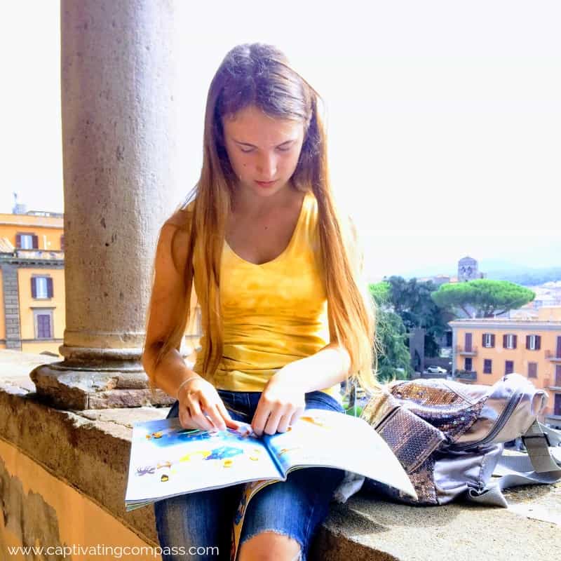 image of girl sitting on wall doing schoolwork in Italy